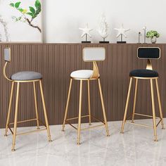 three modern bar stools in front of a wall