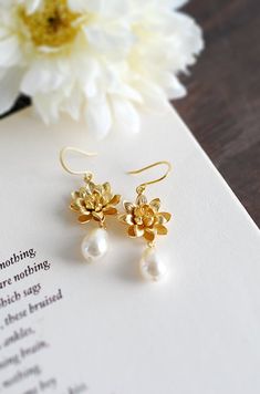 "Gold Lotus and Cream Teardrop Pearl Earrings. Beautiful and classic, these earrings are created from delicate matte gold plated over brass lotus and Swarovski cream teardrop pearls. The total length of these earrings is approx. 1.7\" (43mm) Gold lotus: 17mm across in beautiful matte gold finish Ear wires: tarnish resistant matte gold plated over brass hooks If you would like these Swarovski pearls in a different color, please feel free to contact me for a custom listing. ♥ Click the link below Delicate Teardrop Flower Earrings For Weddings, Wedding Pearl Drop Teardrop Earrings, Delicate Gold Teardrop Earrings For Wedding, Pearl Drop Teardrop Wedding Earrings, Wedding Teardrop Pearl Drop Flower Earrings, Classic White Flower Earrings For Wedding, Classic White Flower Wedding Earrings, Bridal Gold Earrings, Teardrop Pearl Earrings