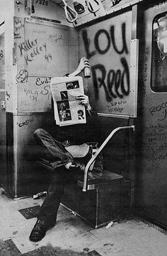 a man sitting on top of a chair next to a wall covered in graffiti