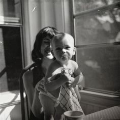 an old black and white photo of a woman holding a baby