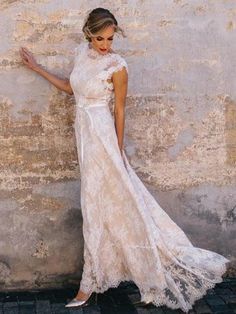 a woman in a white dress leaning against a wall