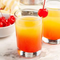 two glasses filled with orange juice and cherries