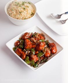 a white plate topped with meat and veggies next to a bowl of rice