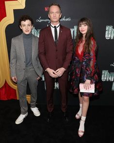 three people standing next to each other on a black carpet