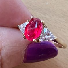 a woman's hand holding a pink and white ring with two diamonds on it