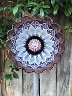 a decorative glass dish sitting on top of a wooden table next to a tree branch