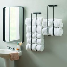 a bathroom with towels hanging on the wall and a mirror in the corner next to it