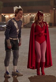 a man and woman dressed up as superheros standing next to each other in an empty parking lot