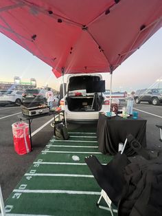 the back end of a white van parked in a parking lot next to a football field