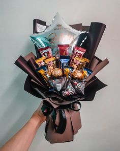 a hand holding a bouquet of chocolates and candies