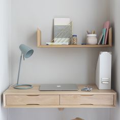 a laptop computer sitting on top of a wooden desk next to a shelf filled with office supplies