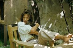 a woman sitting on a wooden bench holding a cat