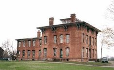 an old brick building sitting on top of a lush green field