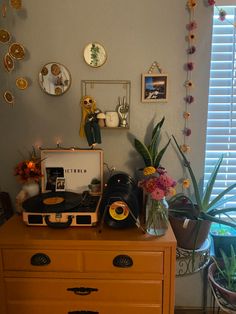 a record player sitting on top of a dresser next to a potted plant and window