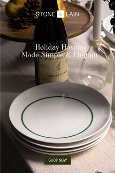 the table is set with plates, wine bottle and vases for holiday hosting made simple & elegant