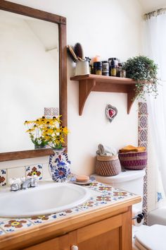 a bathroom with a sink, mirror and toilet in it's corner area next to a window