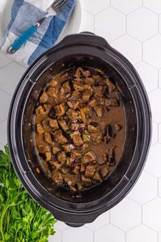 an overhead view of a crock pot filled with meat and vegetables on a table