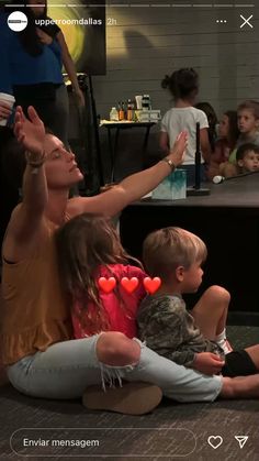 a group of people sitting on the floor with their hands in the air and clapping