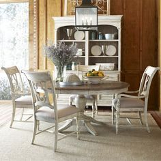 a dining room table with chairs and plates on it in front of a china cabinet