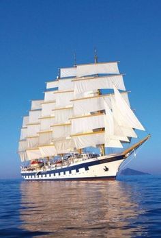 a large white sail boat floating on top of the ocean