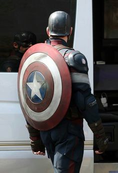 captain america is getting ready to board the bus with his helmet on and shield in hand