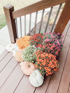 some pumpkins and flowers are sitting on the porch