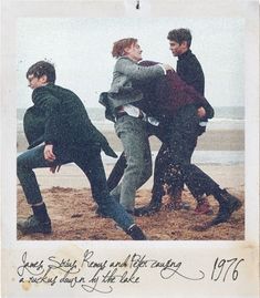 four people are playing in the sand at the beach and one person is falling off his jacket