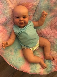 a baby laying on top of a pink and blue blanket in the middle of a bed