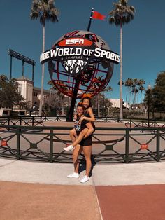 two girls posing in front of the espn world of sports sign