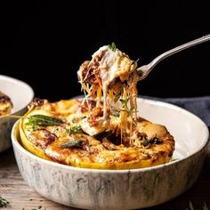 a spoonful of pasta being lifted from a bowl with another dish in the background