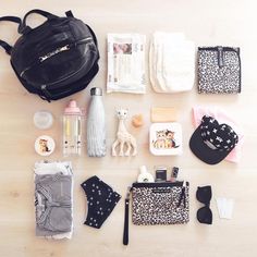 the contents of a diaper bag laid out on top of a wooden floor next to other items