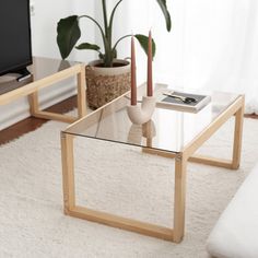 a living room with two glass tables and a white rug on the floor in front of a flat screen tv