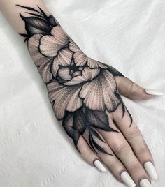 a woman's hand with black and white flowers tattooed on the left arm,