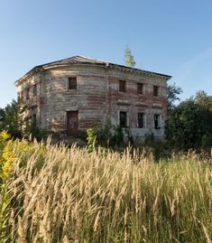 an old brick building sitting in the middle of tall grass