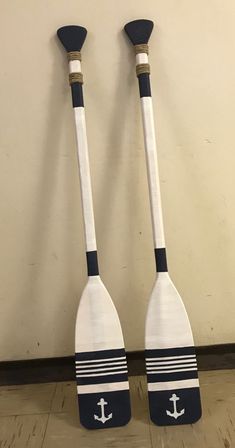 two wooden paddles with black and white stripes, one has an anchor on it