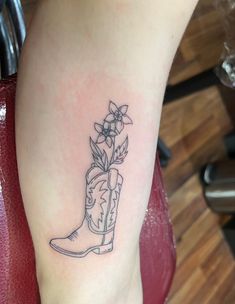 a tattoo on the leg of a woman with boots and flowers in it's boot