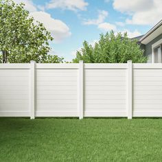 a white vinyl fence in front of a house with green grass and trees behind it