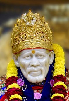 a white statue with a crown on it's head and some flowers around his neck