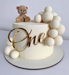 there is a cake with white frosting and a teddy bear on top that says one