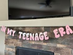 the fireplace is decorated with pink and black letters that spell out in my teenage era