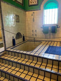 a bathroom with tiled walls and flooring next to a window