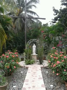 a garden with lots of plants and flowers on the ground, along with a statue in the middle