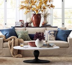 a living room filled with lots of furniture and flowers on top of a coffee table