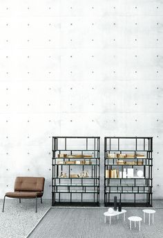 two chairs and a table in front of a wall with bookshelves on it