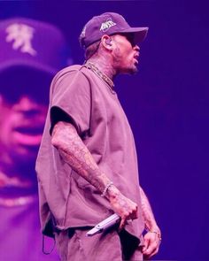 a man with tattoos on his arm holding a knife in front of a purple background