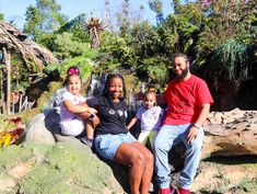 two adults and three children sitting on rocks in front of a waterfall at disney's animal kingdom