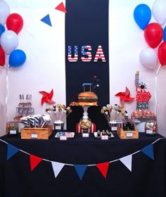 an american themed dessert table with red, white and blue balloons on the wall behind it