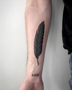 a man's arm with a black feather tattoo on it