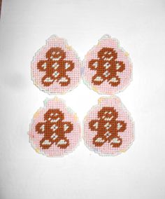 four cross stitch monkey coasters sitting on top of a white tablecloth covered surface