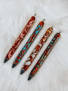 four pens are lined up on top of a white furnishing area, one is red and the other is blue